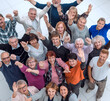 © ASDF - group of happy elderly people standing with their hands up .