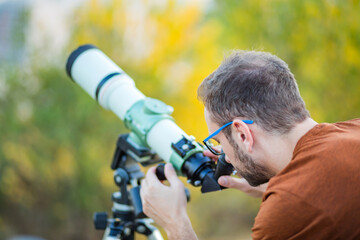 Wall Mural - amateur astronomer looking at the sky with a telescope.