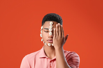 Poster - Portrait of handsome young man with flowers on face against color background