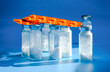 Medical bottles for injection with white powder and drug blister packs on blue background