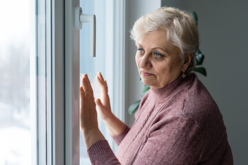 Portrait of senior woman standing at the window at her home