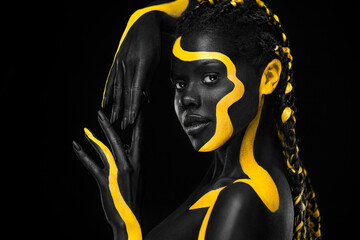 Wall Mural - Yellow and black body paint. Woman with face art. Young girl with colorful bodypaint. An amazing afro american model with makeup.