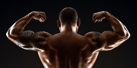 Male bodybuilder with light stubble with a naked torso posing against a dark background. The concept of a fitness club, doing sports, weightlifting. Copy space.