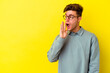 © Asier - Young caucasian man isolated on yellow background is saying a secret hot braking news and looking aside