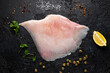 Fresh Ray wings fish with herbs on rustic black background
