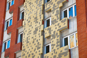 Poster - Mineral wool panels installed on wall facade of building. Thermal insulation of building walls. Yellow fiberglass plates, insulating house facade panels. Rock wool, modern reconstruction of building