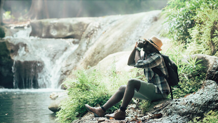 Wall Mural - African man traveler take photo at the waterfall.16:9 style