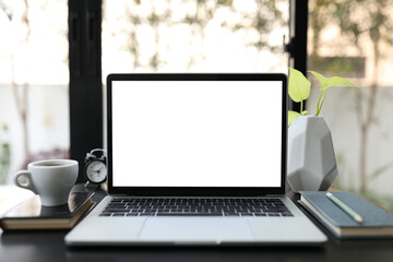 White screen laptop with notebook and coffee cup on table work from home