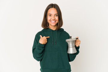 Young hispanic woman holding a coffee maker person pointing by hand to a shirt copy space, proud and confident