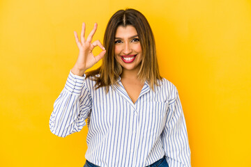 Wall Mural - Young indian woman isolated on yellow background cheerful and confident showing ok gesture.