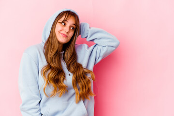 Wall Mural - Young caucasian woman with hood isolated on yellow background touching back of head, thinking and making a choice.