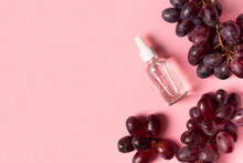 Beauty Concept With Bottle Of Serum And Bunch Of Grape On Pink Background