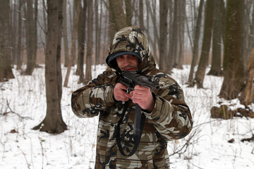 The man with vintage machine gun in the snowy forest