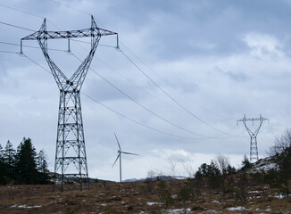 windmill farm next to power lines during wintertime in norway. clean energy concept