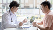 © Puwasit Inyavileart - Young Asian man in a white robe talks to a man, Doctors diagnose diseases and give advice or treatment solutions to patients in the hospital examination room, Explaining medical examination results.