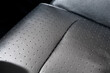 Close-up detail view of modern black perforated dotted ventilated luxury car seat. Part of dark vehicle interior. Auto detailing and leather polish skin cleaning wash and care concept