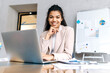 © Kateryna - Attractive female employee is sitting at the desk, smiling and looking at the camera. Beautiful african american businesswoman using laptop, working on project or distantly studying