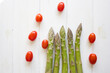 Green Asparagus ans cherry tomatoes on white wood background
