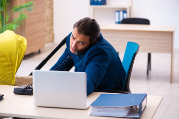 Young male employee looking after kid at workplace