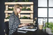 © epiximages - pretty, young businesswoman with a black and white checked shirt and black glasses sits in a sustainable, ecological office and works on her computer