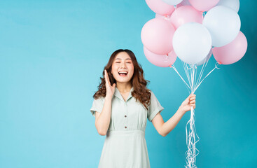 Wall Mural - Young Asian girl holding balloons with happy expression on background