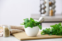 Mortar With Mint And Pestle On Light Table In Kitchen