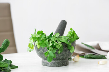 Mortar with herbs and pestle on light table