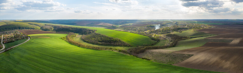 Wall Mural - aerial view of beautiful countryside with green rolling field in golden hour before sunset