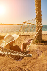 Travel and vacation concept - Woman relaxing on hammock on the beach