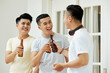 © DragonImages - Group of Asian men having fun together while drinking beer at home