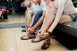 © DragonImages - Close-up of young people preparing for bowling game putting on the special shoes