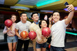 © DragonImages - Group of Asian friends posing with balls at camera of mobile phone while playing bowling