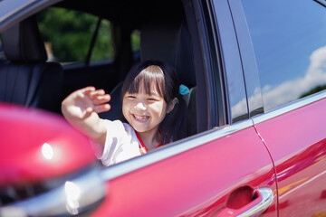 車から手を振る小さな女の子