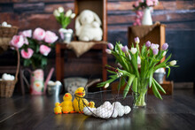 Basket With White Easter Eggs On The Foreground And A Vase With Flowers, Ducks And Easter Decoration