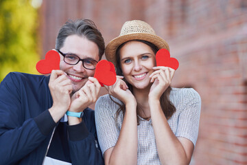 Wall Mural - Adult romantic couple holding hearts on the walk in the city