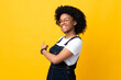 Young African American woman isolated on yellow background pointing back