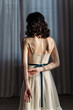 © Alex Li - Cute young girl stands in the studio on the background of curtains. Beautiful naked back is visible.