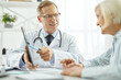 © Kostiantyn - Cheerful doctor talking with old woman in clinic