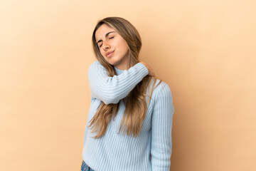 Wall Mural - Young caucasian woman isolated on beige background suffering from pain in shoulder for having made an effort