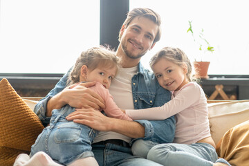 Wall Mural - Portrait of handsome father and his cute daughters hugging and smiling.