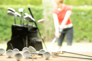 Sticker - Golf balls, golf equipment and golf club on table on driving range with golfer in background