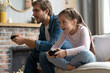 © opolja - family, gaming and entertainment concept - happy father and little daughter with gamepads playing video game at home.