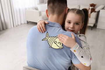 Sticker - Cute little girl sticking paper fish to father's back at home