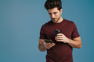 Canvas Print - Focused handsome man drinking coffee and using mobile phone