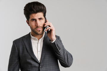 Canvas Print - Serious young man in jacket posing and talking on mobile phone