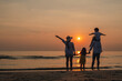 © Garun Studios - Happy asian family together on the beach in holiday.  of the family holding hands enjoying the sunset on the beach.Summer,Family and vacations concept.