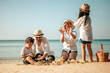 © Garun Studios - Happy parents and kid having fun with playing sand in summer vacation on the beach.Travel,Happy family and vacation concept.
