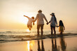© Garun Studios - Happy asian family jumping together on the beach in holiday. Silhouette of the family holding hands enjoying the sunset on the  beach.Happy family and vacations concept.