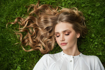 Wall Mural - young blonde woman relaxing on green grass outdoor