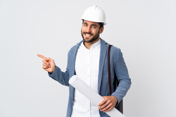 Wall Mural - Young architect man with helmet and holding blueprints isolated on white background pointing finger to the side